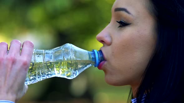 Slowmotion Detail of Young Beautiful Woman Stands and Drinks From Plastic Bottle