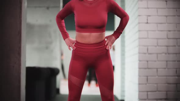 Young Woman in Red Sports Suit Doing Fitness Exercises in the Gym  Bending Forwards with Her Body