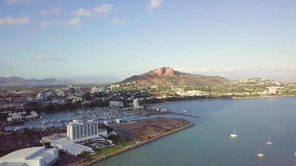 Drone panning right to left revealing Townsville city with Castle Hill in the background on a sunny