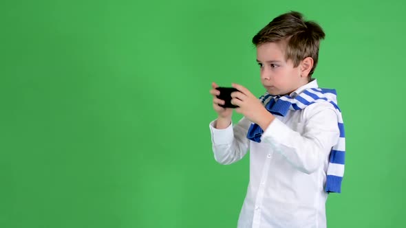 Young Handsome Child Boy Photographs with Smartphone - Green Screen - Studio