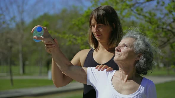 Focused Senior Woman Exercising in Summer Park with Coach