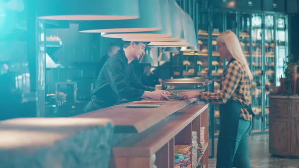 A Waitress is Taking Ordered Food From a Cook