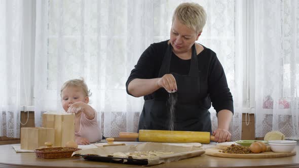 Cute Baby Granddaughter Helps Granny Mixing Dough for Pastry and Puts Flour