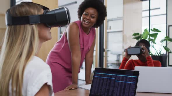 Diverse female office colleagues gesturing while wearing vr headset at office