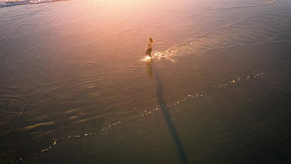 Aerial shot of fit asian woman jogging on the beach at sunset