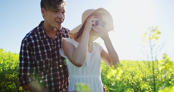 Couple taking picture from camera in mustard field