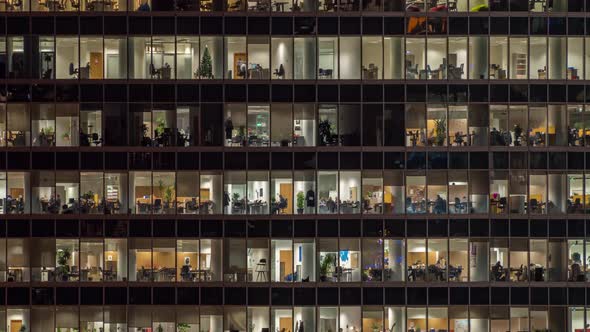 Panning up view of office windows with working people