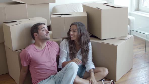 Young Caucasian Couple Sitting on Floor Near Carton Boxes