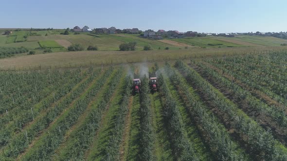 Aerial view of tractors irrigating an apple plantation