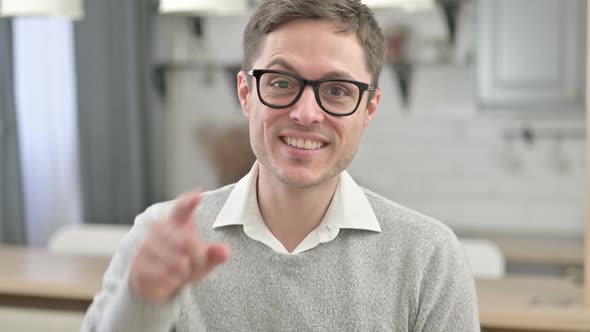 Inviting Young Man Pointing Toward Camera