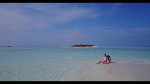 Guy and girl happy together on tropical lagoon beach trip by clear water with white sandy background