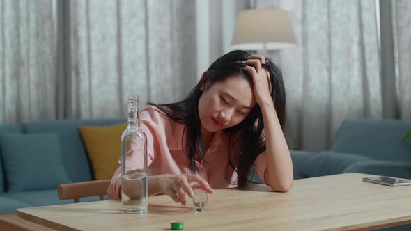 Drunk Asian Woman Pouring Vodka In A Shot Glass And Cheer To Camera Before Drinking At Home