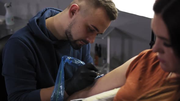 Portrait of a Tattoo Artist Demonstrates the Process of Getting Colour Tattoo