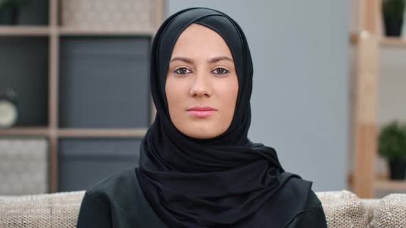 Portrait of Happy Young Ethnic Muslim Beautiful Woman in Black Hijab Posing on Couch Medium Closeup