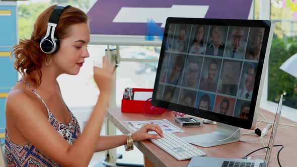 Female executive using laptop and computer while listening to music on headphones 