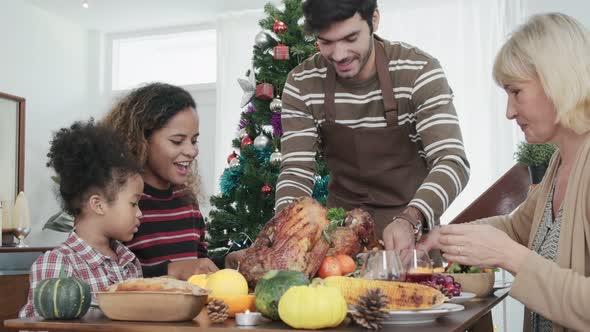 family having holiday dinner and cutting turkey Thanksgiving Celebration