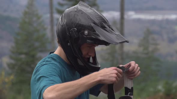 A young man mountain biker putting on goggles.