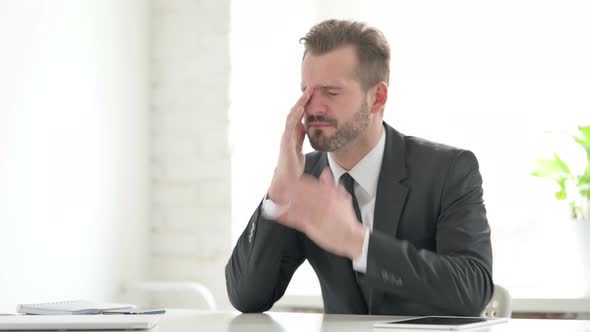 Young Businessman Feeling Stressed While Sitting in Office