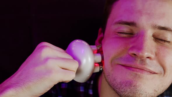 Young Happy Man Using 3d Massager for Face