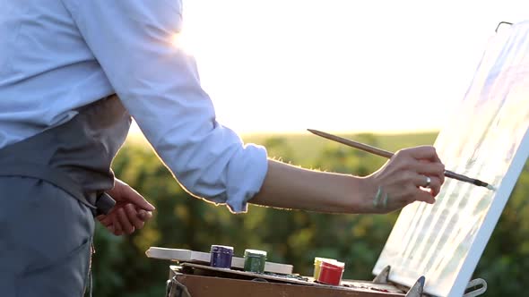 The young artist paints a summer landscape.