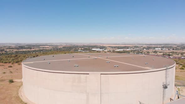 DRONE Shot of Water Supply Tank supplying water to a Town in the Background on a Sunny Day