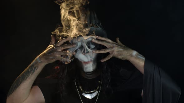 Man in Skeleton Halloween Creepy Skull Makeup Exhaling Cigarette Smoke From His Mouth, Smiling