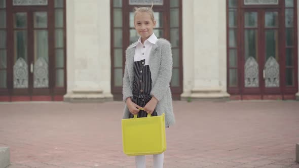 Portrait of Smiling Caucasian Schoolgirl Looking at Camera, Turning, and Walking To School. Camera