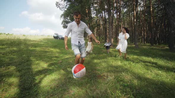 Happy family playing a soccer in the park. Funny kids playing ball. Slow motion.