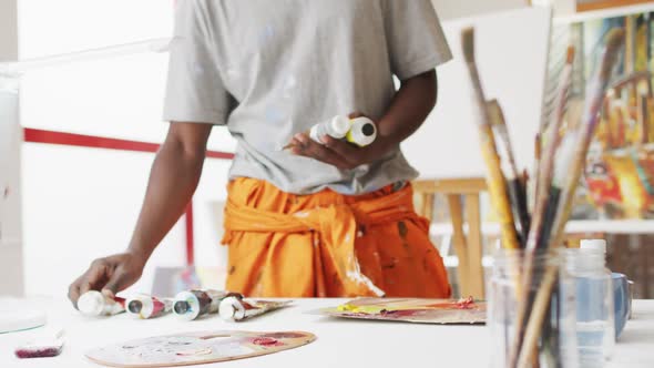 Midsection of african american male painter choosing paint in artist studio