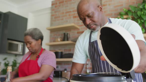 Happy african american senior couple cooking together in kitchen