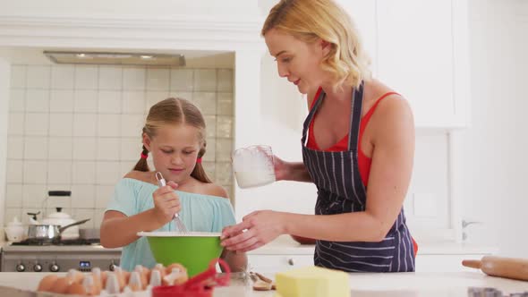 Caucasian mother and daughter baking together in the kitchen at home