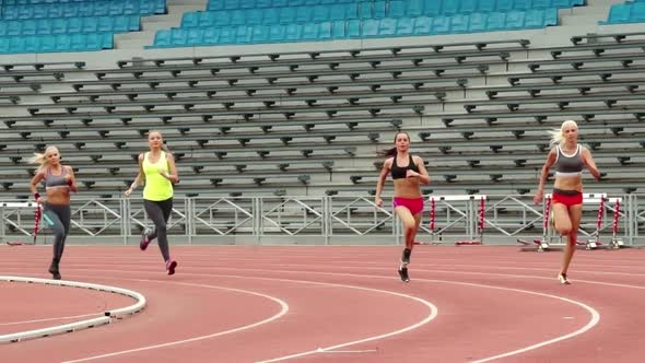 Sportswomen Running along Stadium Tracks