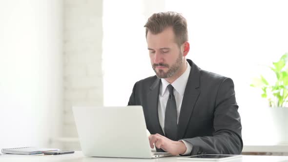 Young Businessman Having Back Pain While Using Laptop in Office