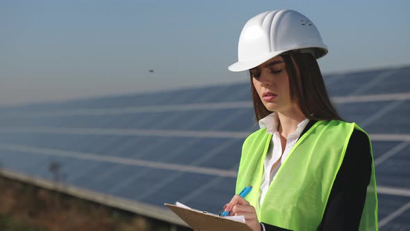 A Female Engineer is Standing Next to Solar Panels