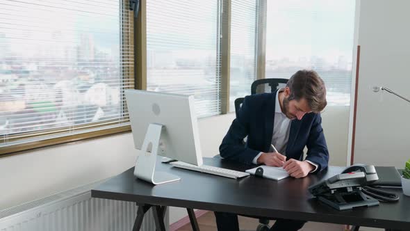 Young Businessman Working at a Computer Sitting at Work Desk Workaholic at Work Manager Writes the