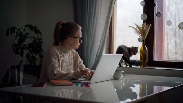 A Young Girl Typing on a Laptop While Working or Studying From Home