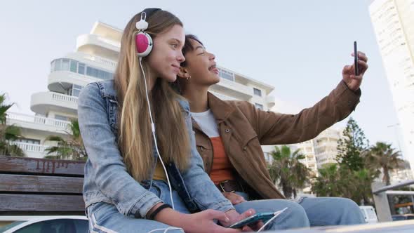 Low angle of a Caucasian and a mixed race girl using their phones