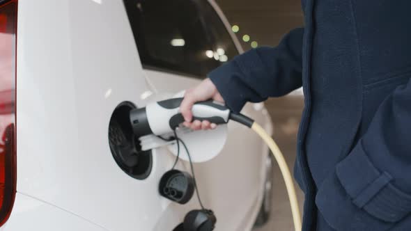 Woman Hand Disconnected Power Cable Supply to Charge Electric or EV Car