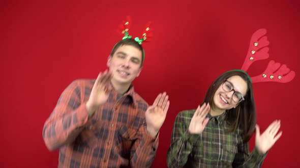 A Young Woman and a Man Are Dancing with a Headband in the Form of Christmas Deer Antlers. Studio