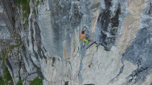 Aerial drone view of a man rock climbing up a mountain.