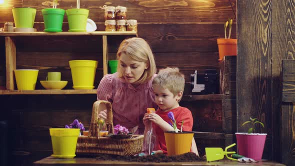 Little Son Helps Mother To Care Plants Flowers. Mom and Son Gardening at Home, Happy Family.