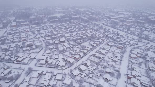 Aerial view of the snow village with private houses and garden plots at winter