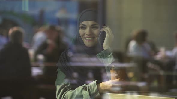 Attractive Young Arab Female Talking on Phone, Spending Free Time in Cafe, Relax