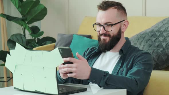 Bearded Man Typing a Sms to His Girlfriend While is Taking a Break From Working