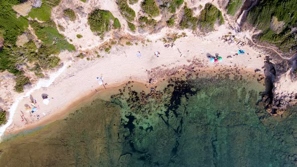 Ascendant aerial drone view of coastline with people sunbathing and relaxing