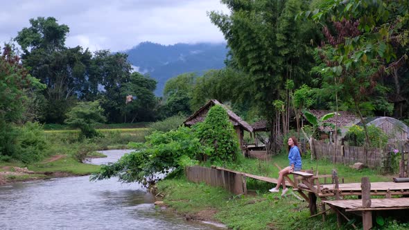 A young asian woman sitting by the river in rural village