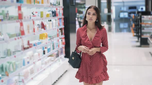 Sexy Young Brunette Girl in Red Dress Goes in Supermarket for Shopping