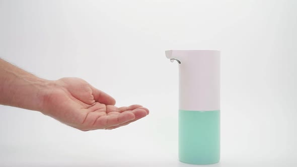 Male Hand and Automatic Dispenser, Disinfectant on an Isolated Background, Close-up. Demonstration