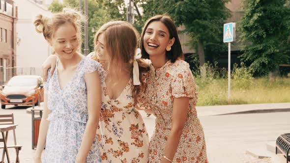Three young beautiful girls posing outdoors at summer sunny day