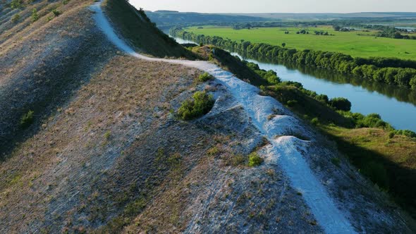 Flight Over Green Hills Fields and White Road on a Sunny Day